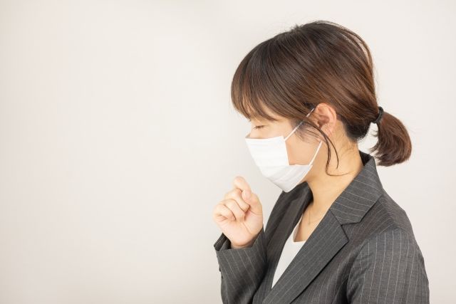 咳き込むマスク姿の女性
